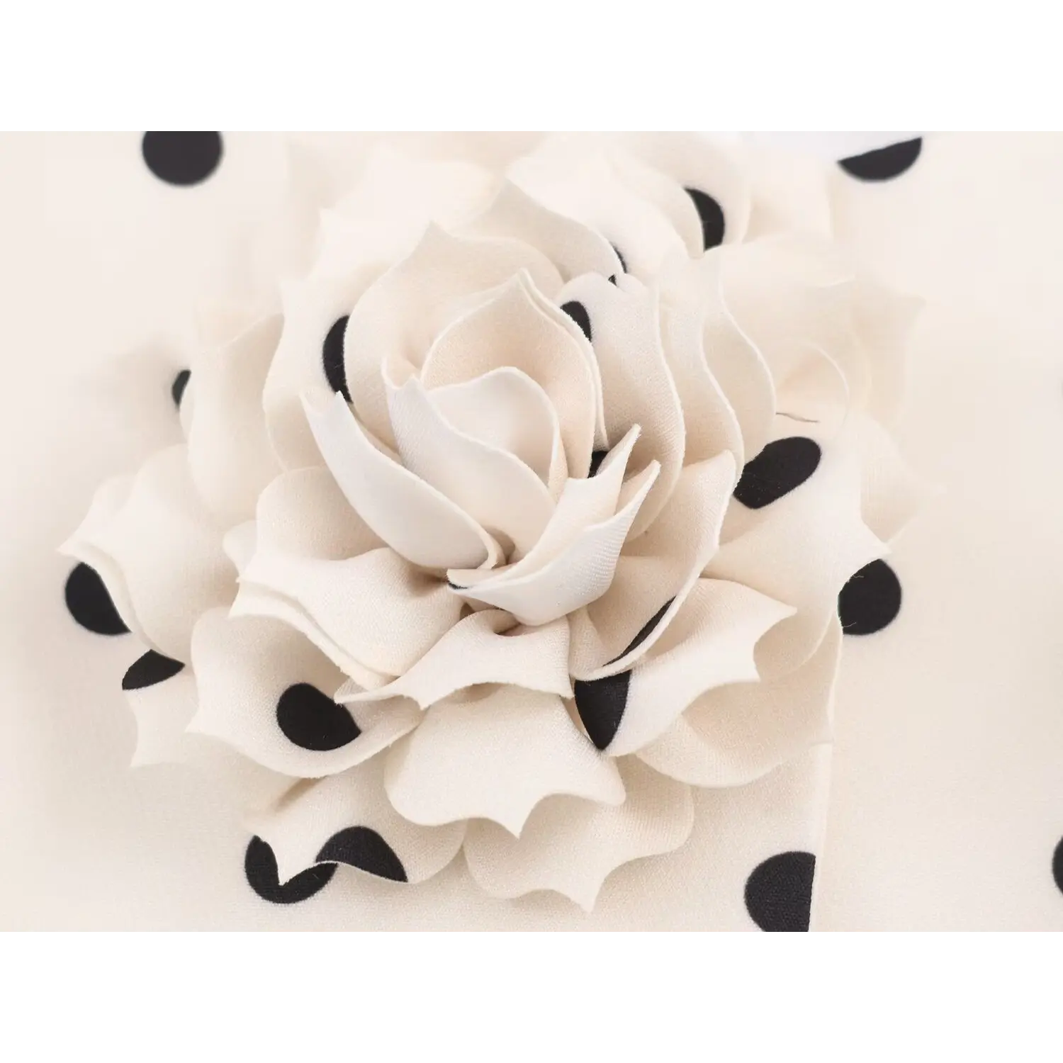Extreme closeup of off-white handmade fabric rose decoration on white polka dot outerwear