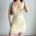 Model slight side front pose yellow flocked mesh mini dress keyhole tie bust short ruffle sleeve mesh bodycon dress