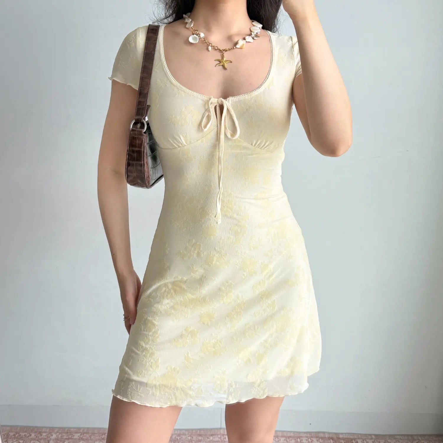 Model slight side front pose yellow flocked mesh mini dress keyhole tie bust short ruffle sleeve mesh bodycon dress