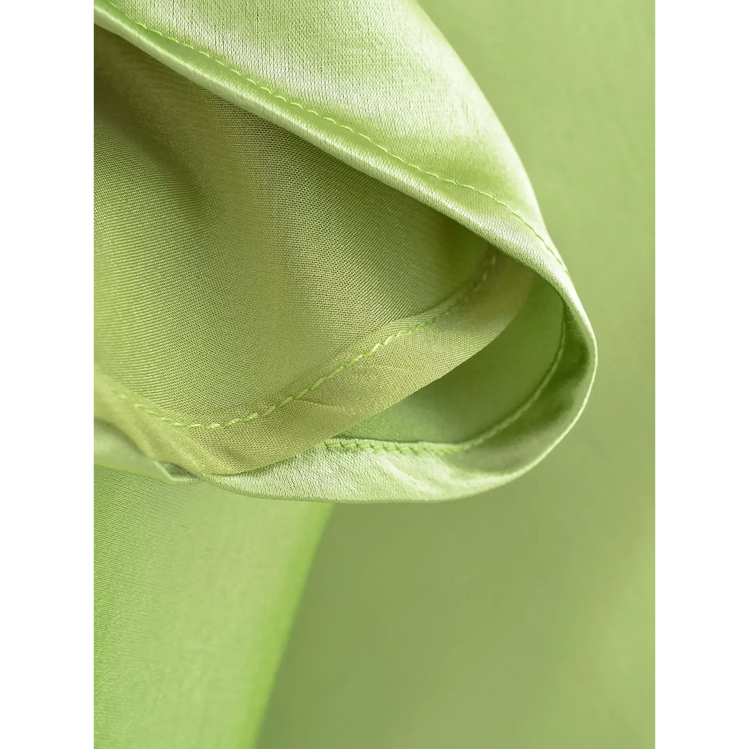 Two-layer fabric close-up of avocado green skirt hem, shiny satin outer layer + soft sheer chiffon inner lining