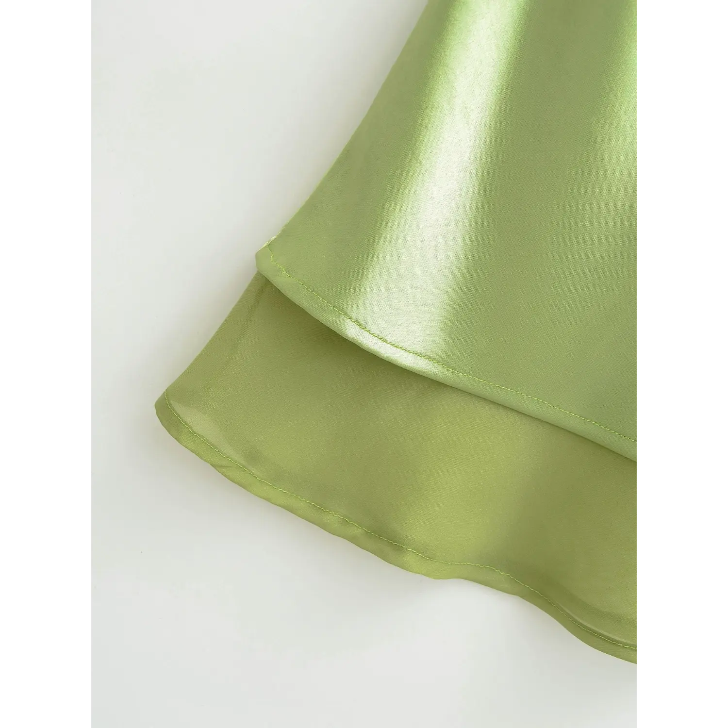 Stitching close-up of avocado green satin skirt hem, double chiffon lining with clean overlock workmanship