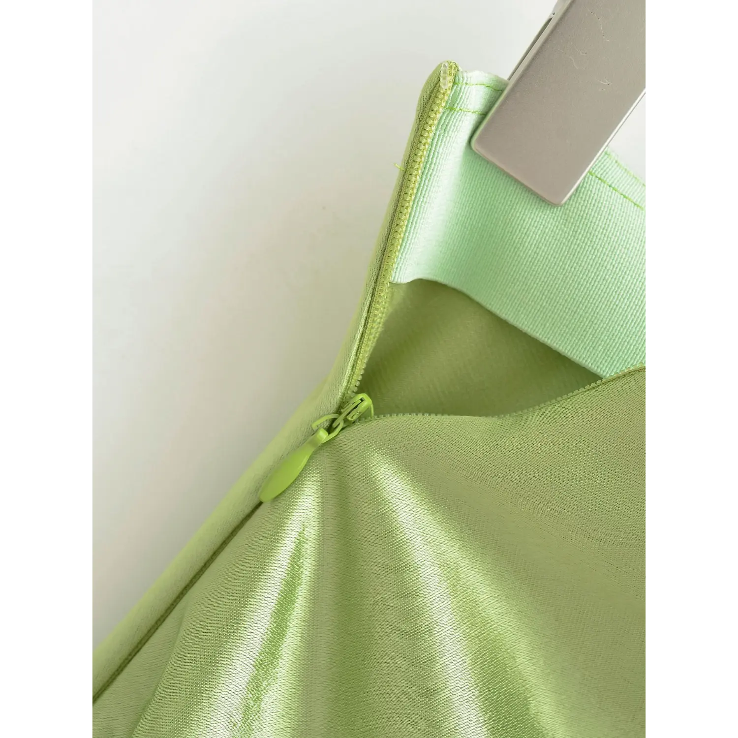 Inside view of invisible zipper on avocado green satin skirt, wide matching waist lining with tidy stitching