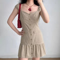 Model wearing beige utility-style mini dress with sweetheart neckline, button-down front, flounce hem, and short sleeves