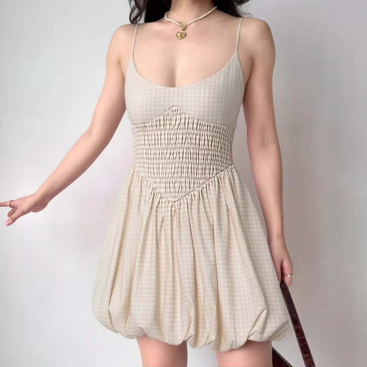 Model wearing beige gingham cami dress with bubble hem and smocked waist