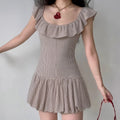 Model wearing beige gingham mini dress with ruffled square neckline, sleeveless design, fitted bodice, and flared bubble hem