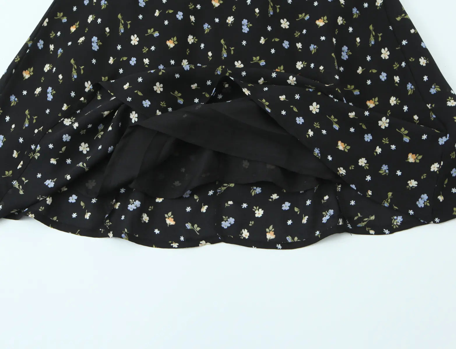 Close-up of layered ruffled hem and lining on black floral halter dress