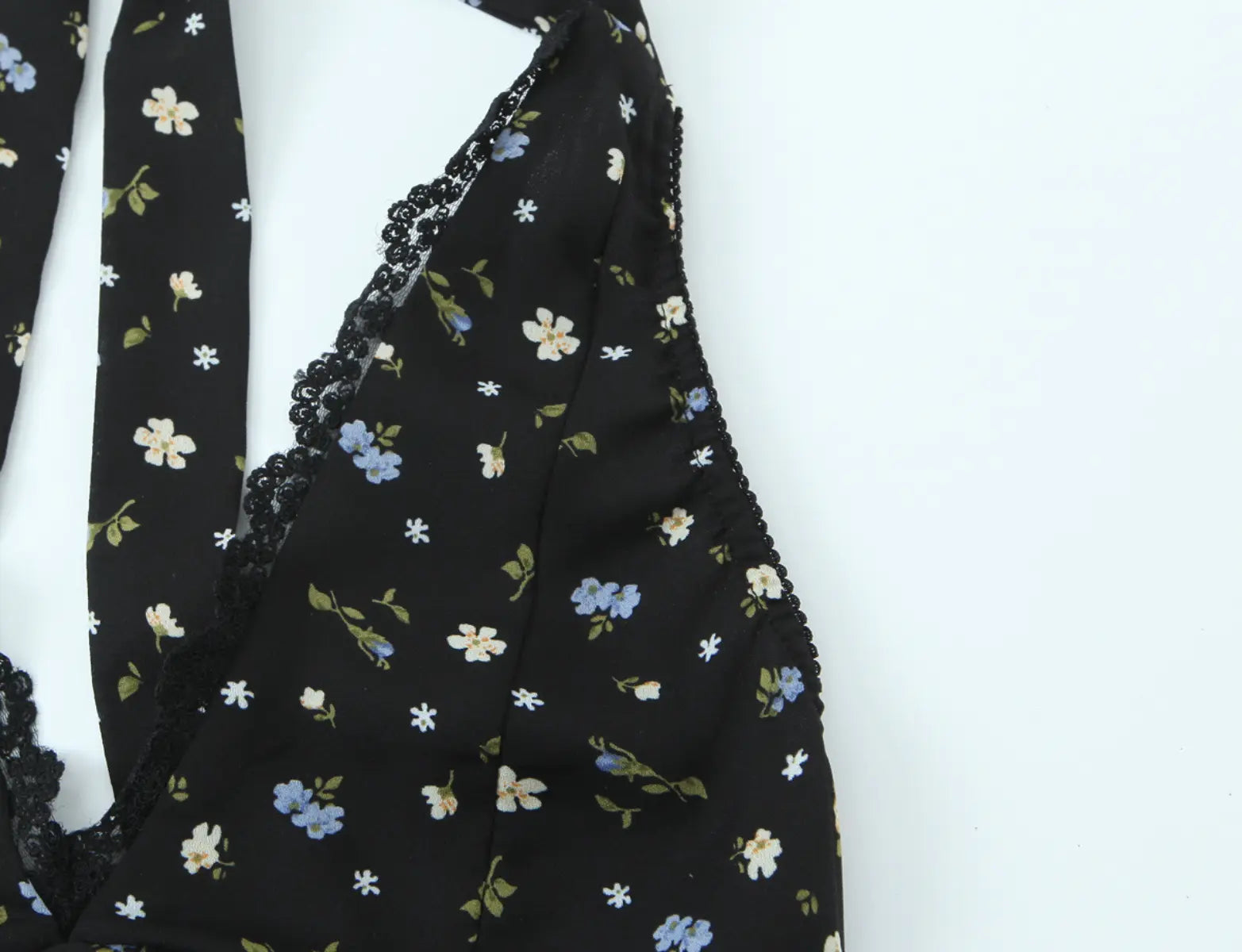 Close-up of scalloped lace trim at the V-neckline of black halter dress