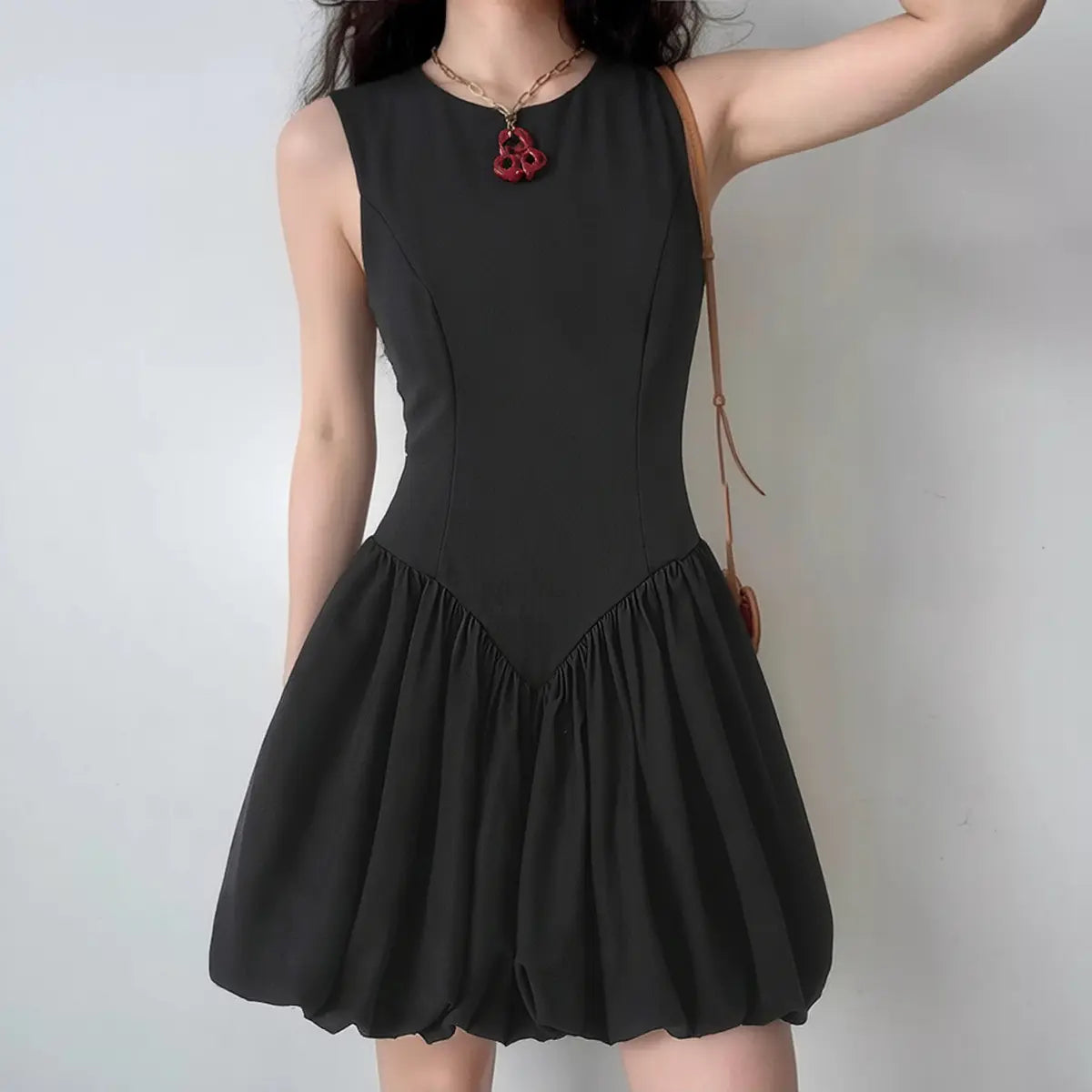 Model wearing black sleeveless mini dress with balloon hem and fitted bodice, elegant A-line party dress
