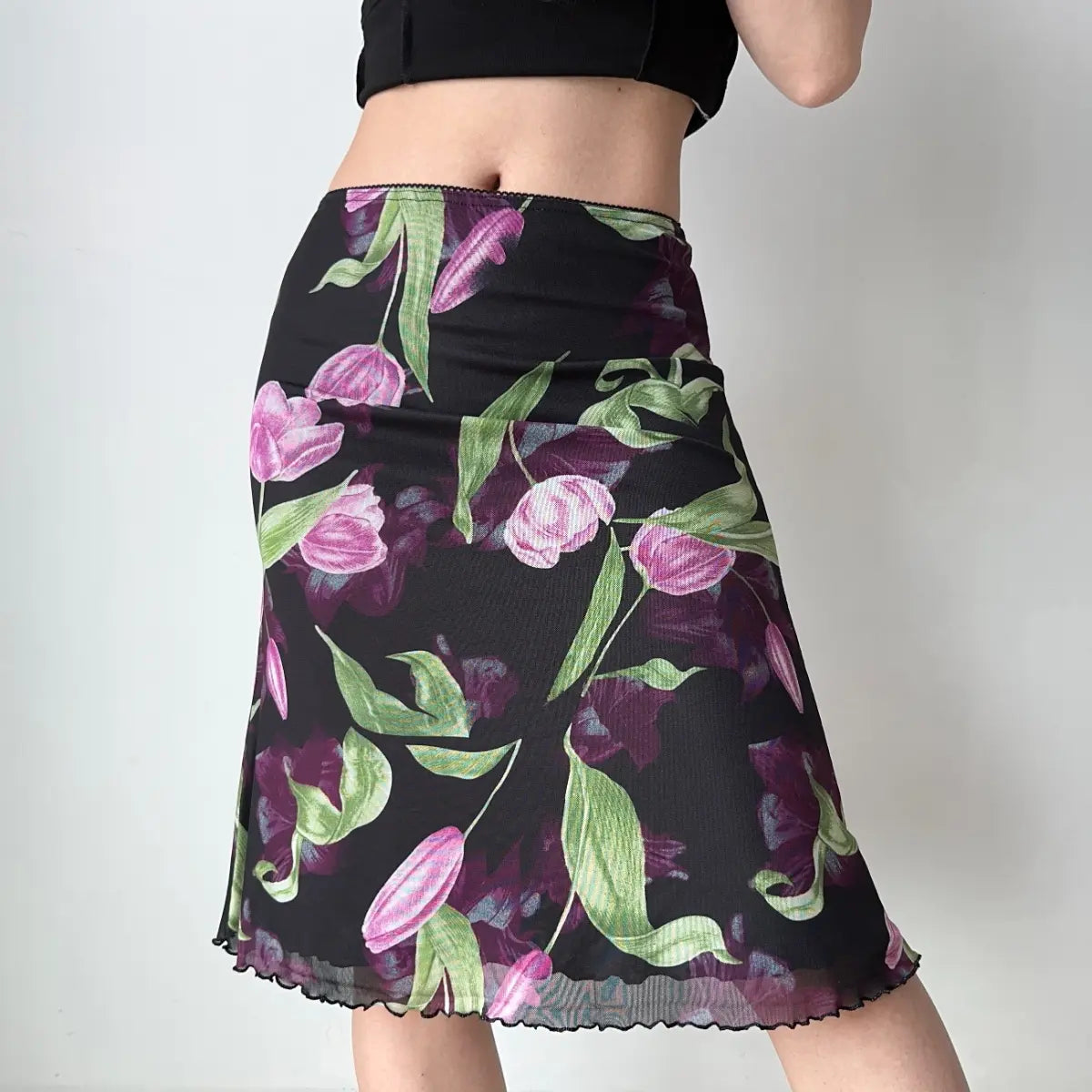 Model wearing black tulip print mesh midi skirt, three-quarter view
