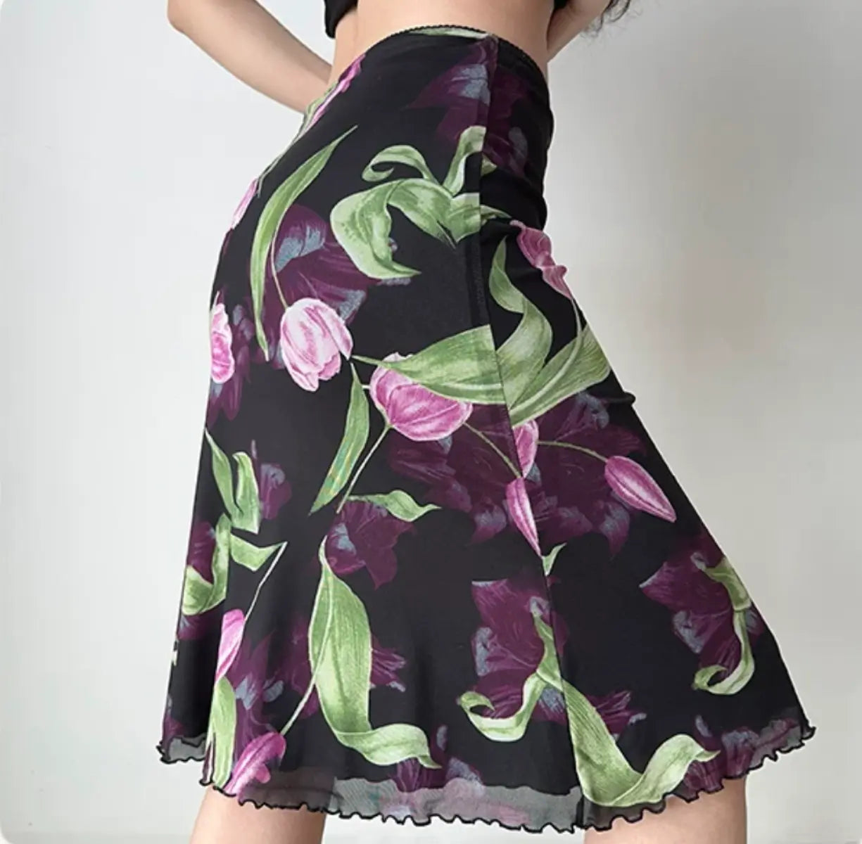Model wearing black tulip print mesh midi skirt, side view