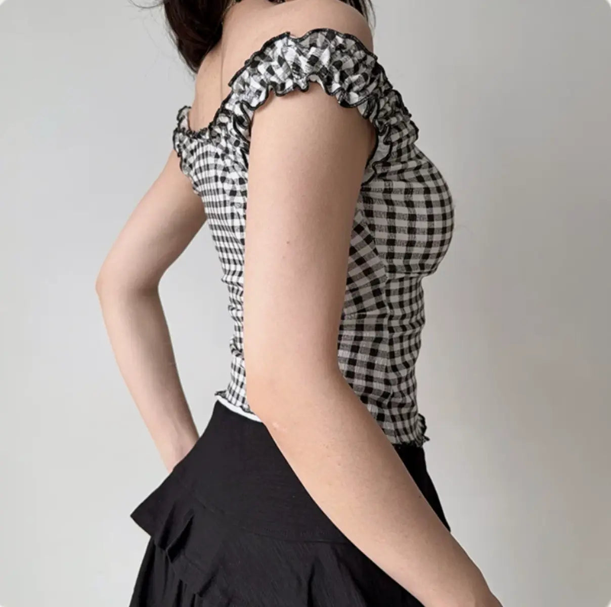 Back view of black and white gingham cami top with ruffled trim and fitted waist