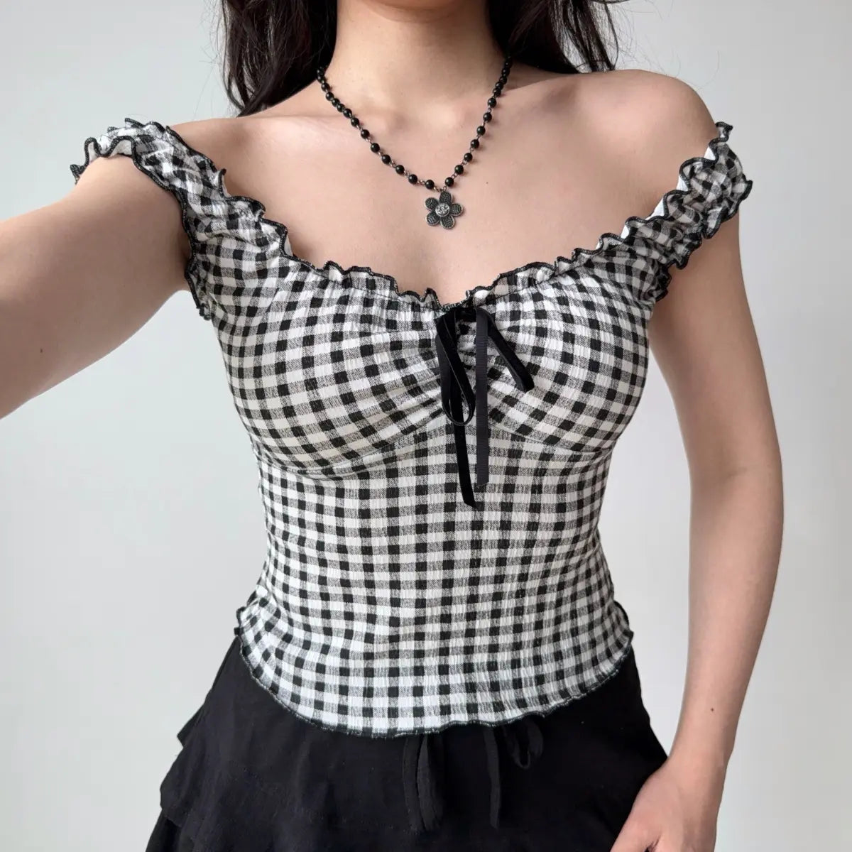 Front view of black and white gingham cami top showing the sweetheart neckline, ruffled trim, and fitted corset-style silhouette