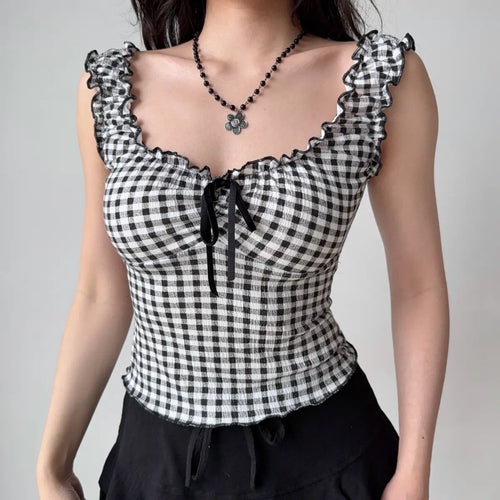 Model wearing black and white gingham cami top with ruffled scallop trim, sweetheart neckline, and front tie detail