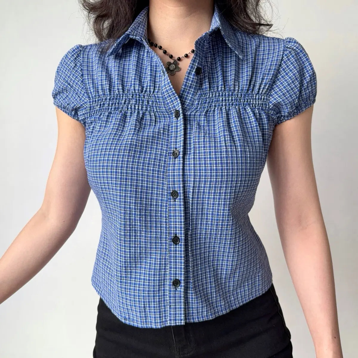 Front view of blue gingham shirt showing the collared neckline, puff sleeves, and fitted waist silhouette