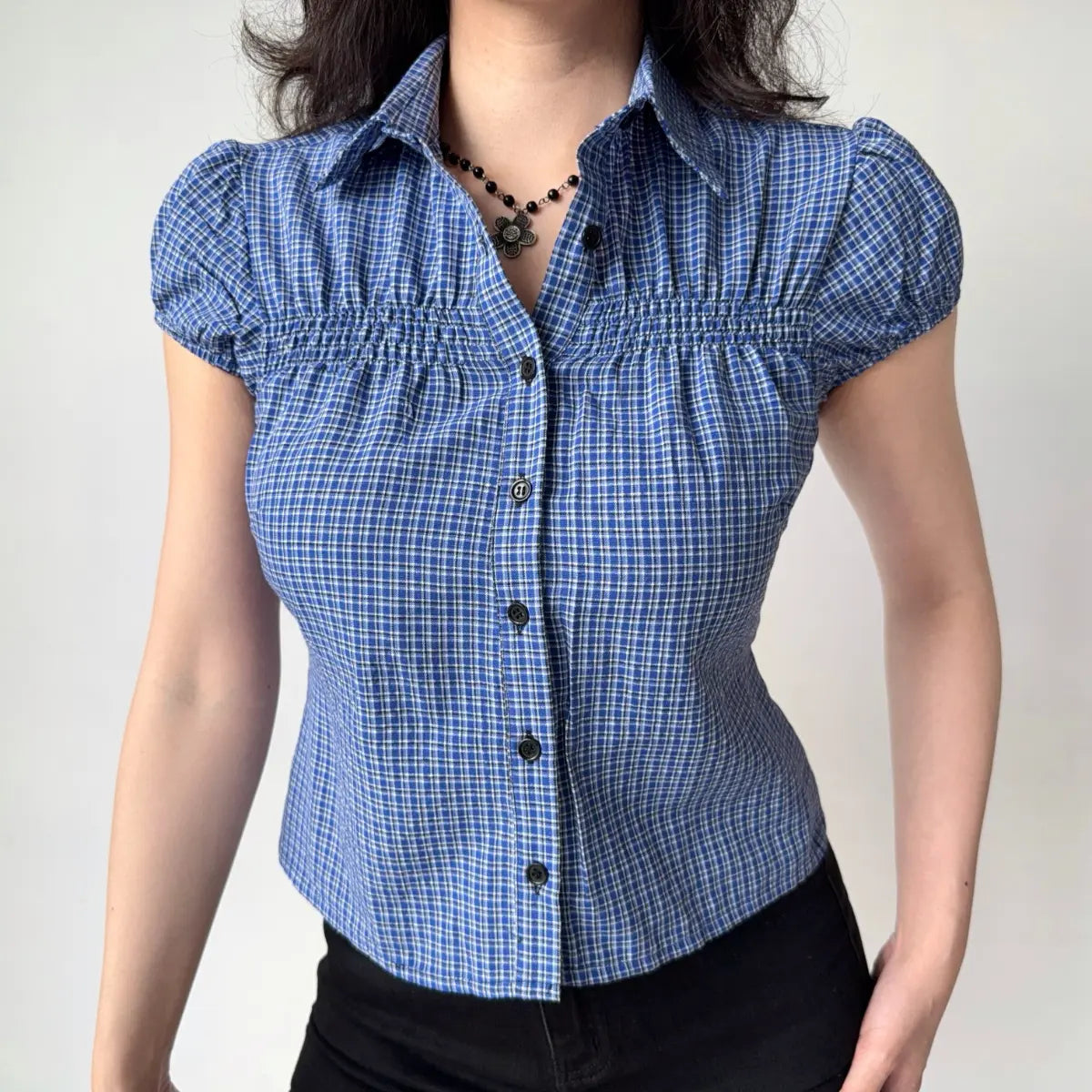 Outfit view of blue gingham shirt styled with black shorts, highlighting the classic checkered pattern