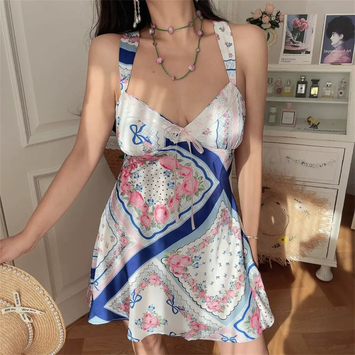 Model wearing blue and pink rose scarf print cami dress with lace trim and bow detail