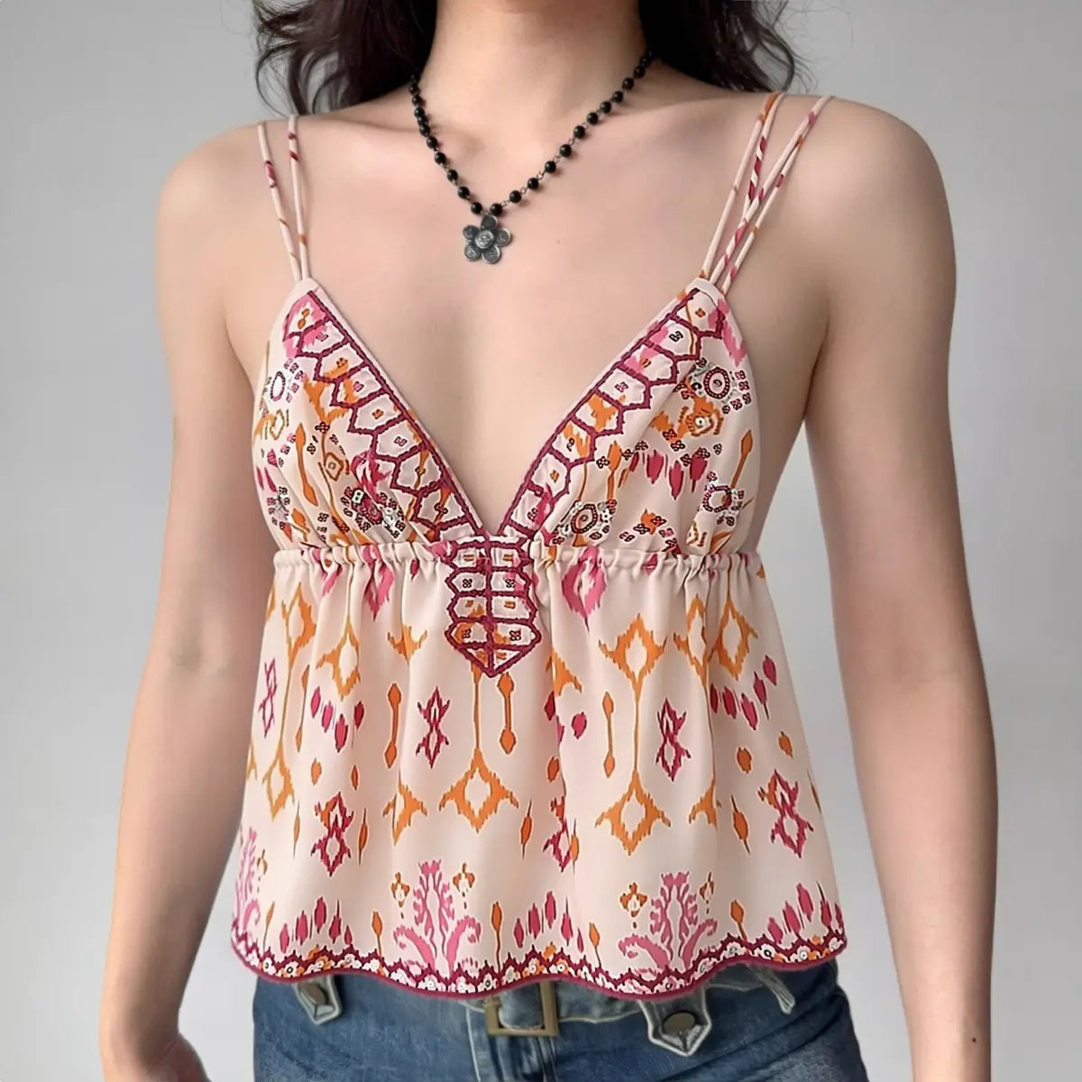 Model wearing boho-print cami top with double straps and peplum hem, flowy tribal-inspired spaghetti-strap top