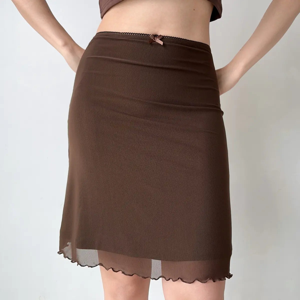 Model wearing brown mesh midi skirt with bow detail, front view