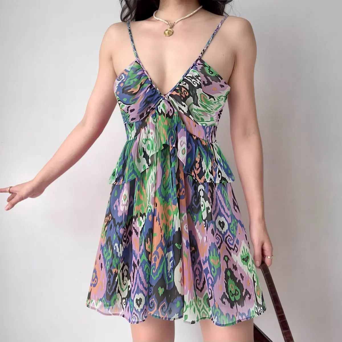 Model wearing colorful ikat print spaghetti-strap mini dress with tiered ruffle hem, bohemian summer dress