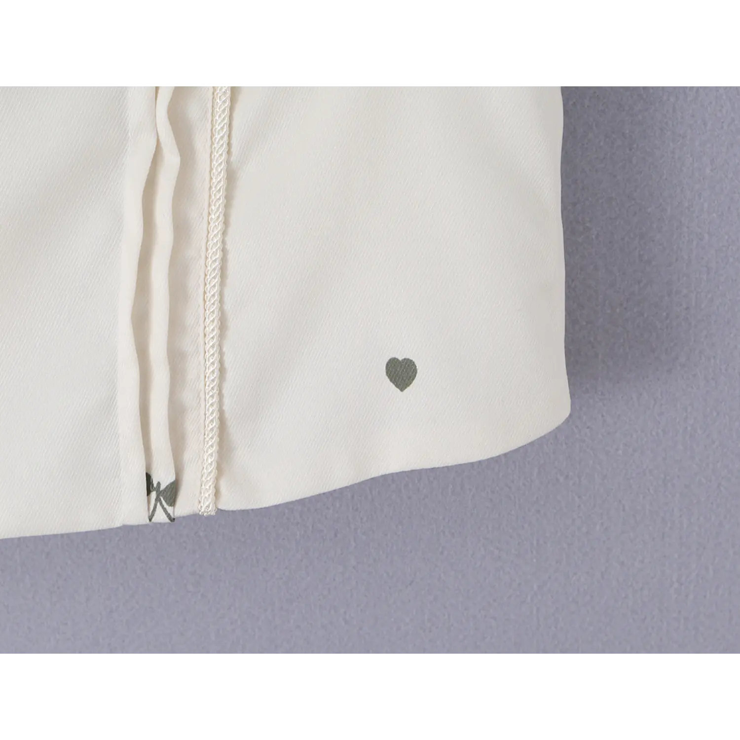 Curved hem close-up with tiny grey heart print on cream cherry corset cami top