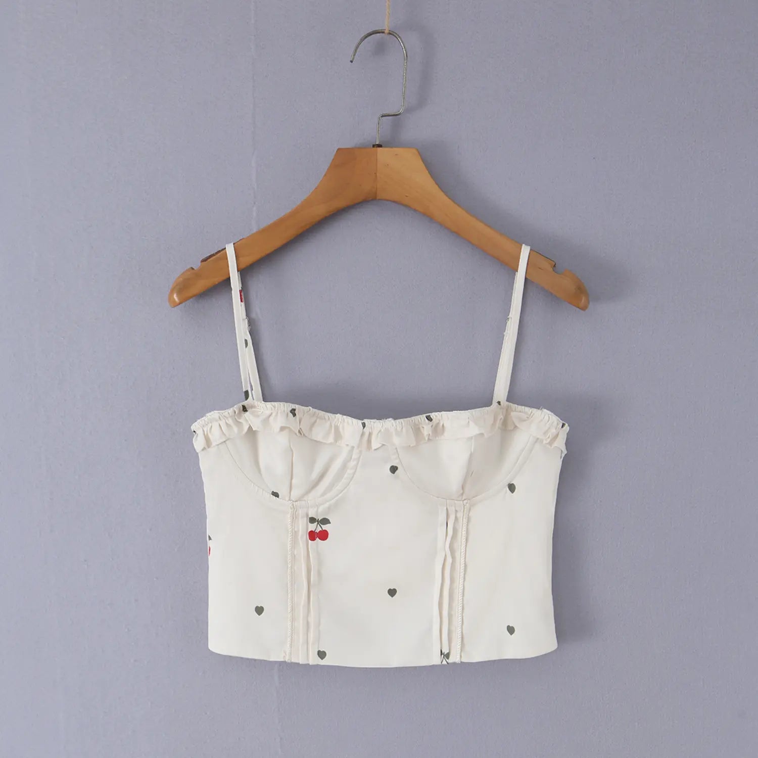 Real shot of cream cherry heart print corset cami hanging on wooden hanger, front ruffle bust structured design