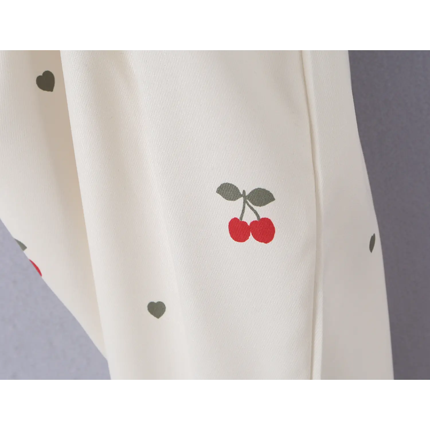 Macro texture shot of vivid red cherry graphic print on soft cream woven fabric