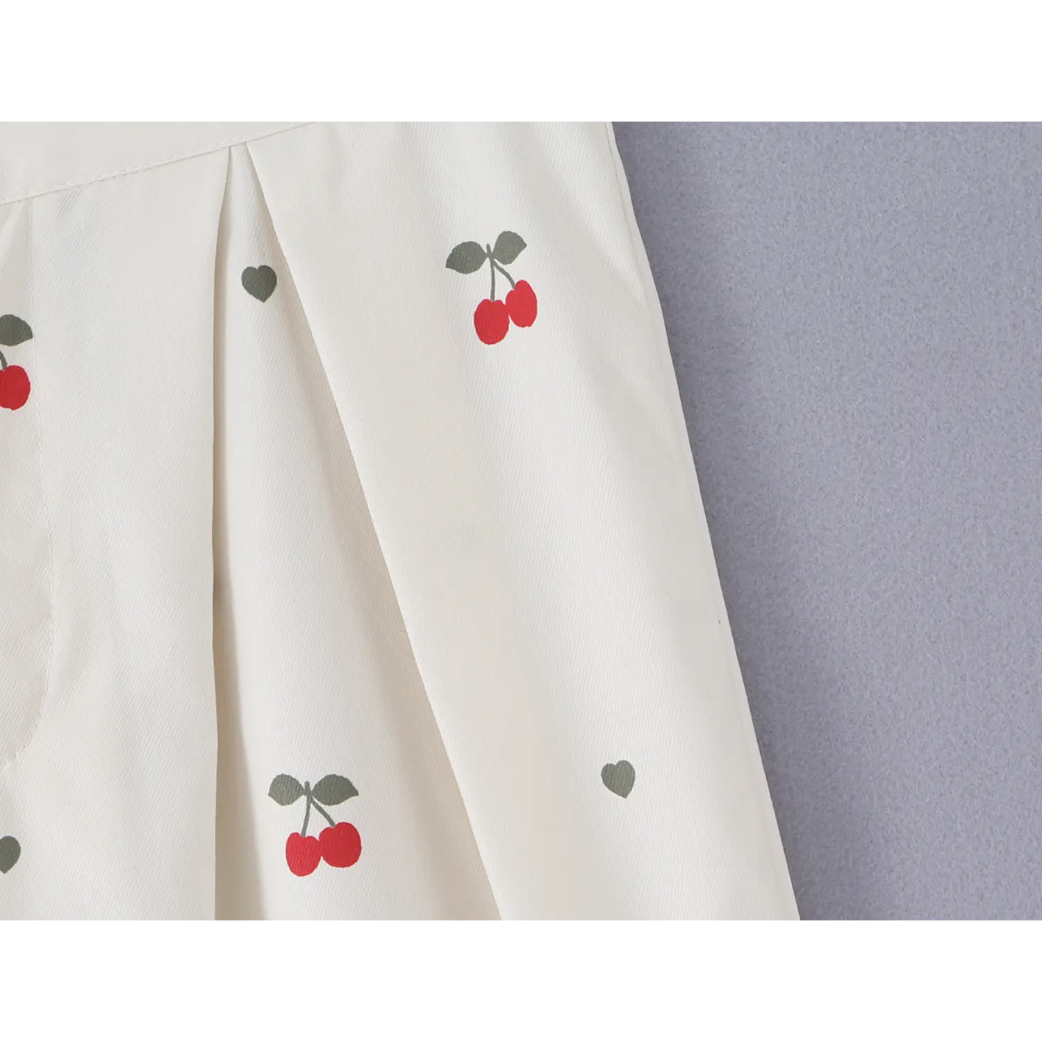Macro texture shot of soft woven fabric with scattered red cherry and mini grey heart graphic print