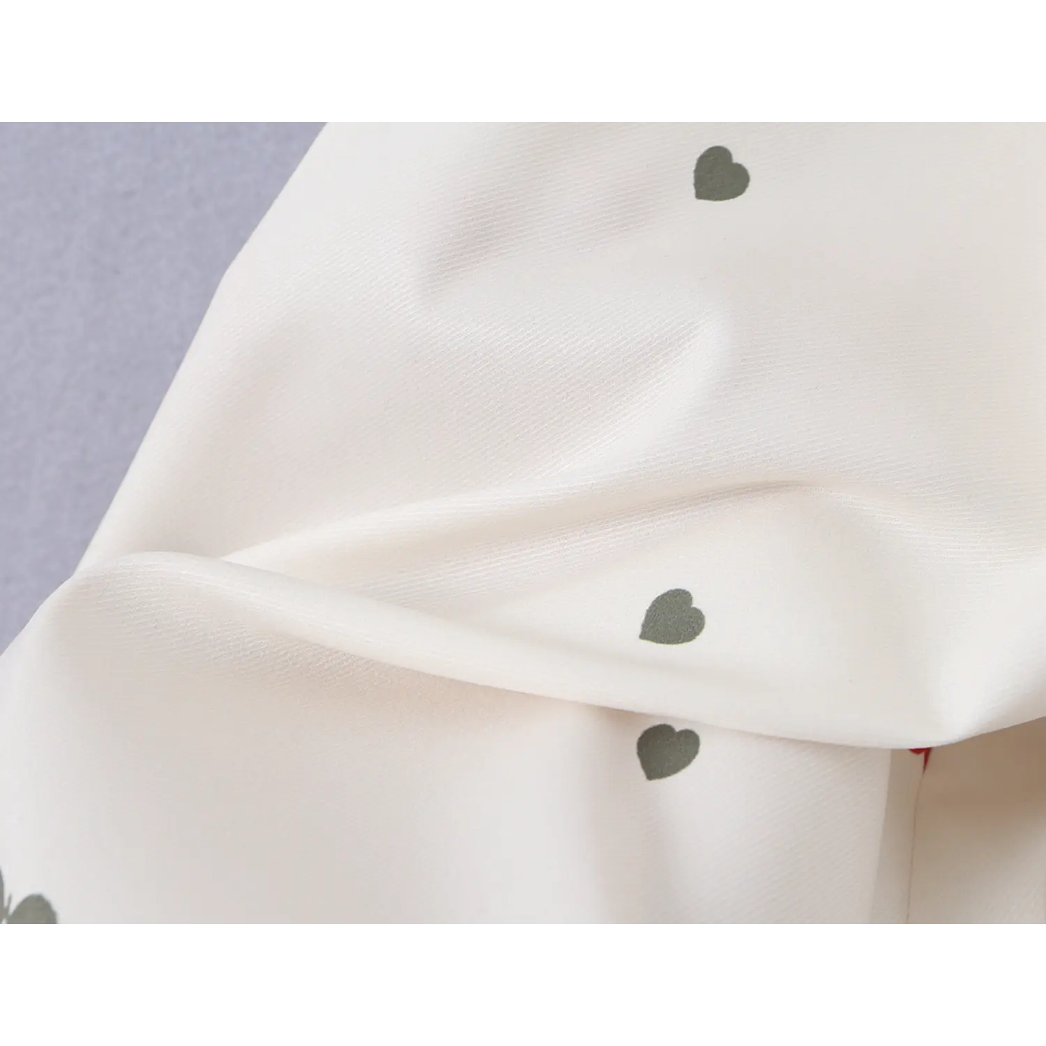 Fabric drape close-up with grey tiny heart print, showing smooth lightweight flowy material