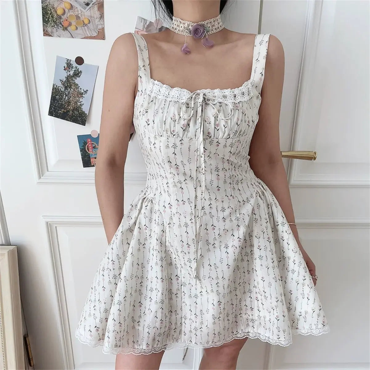 Model wearing cream ditsy floral cami mini dress with lace trim and front tie detail