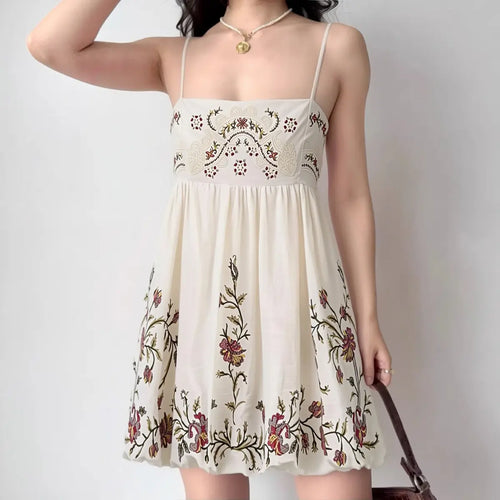 Model wearing cream floral embroidered cami mini dress with spaghetti straps and smocked bust