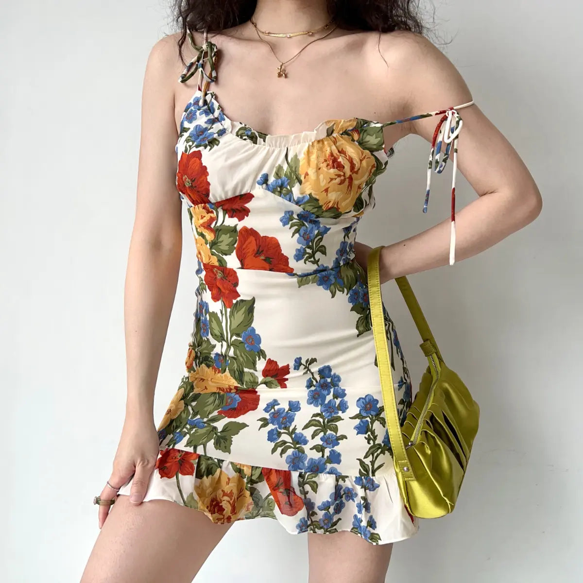 Model wearing cream floral print cami mini dress with tie straps, ruched bust and ruffled hem