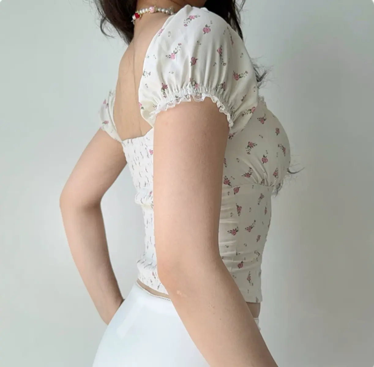 Back view of cream floral print corset-style top with puff sleeves and fitted waist