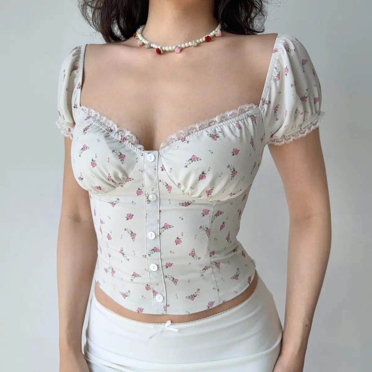 Front view of cream floral print top showing the sweetheart neckline, lace trim, puff sleeves, and fitted corset silhouette