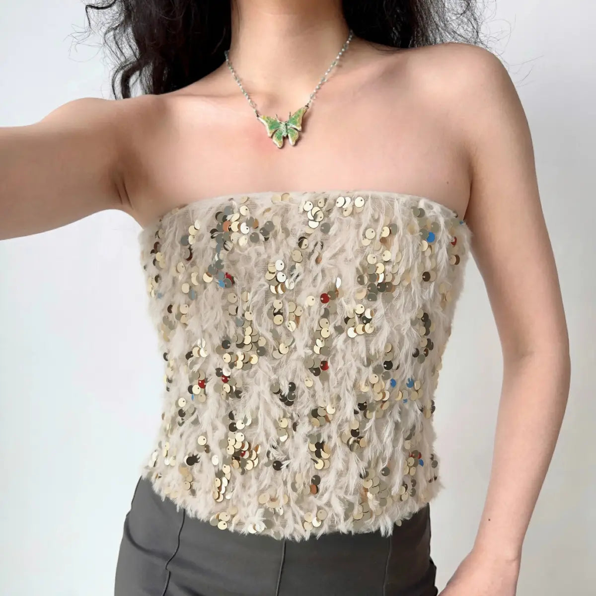 Model wearing cream sequin fuzzy strapless corset top, glamorous party-ready bustier-style top
