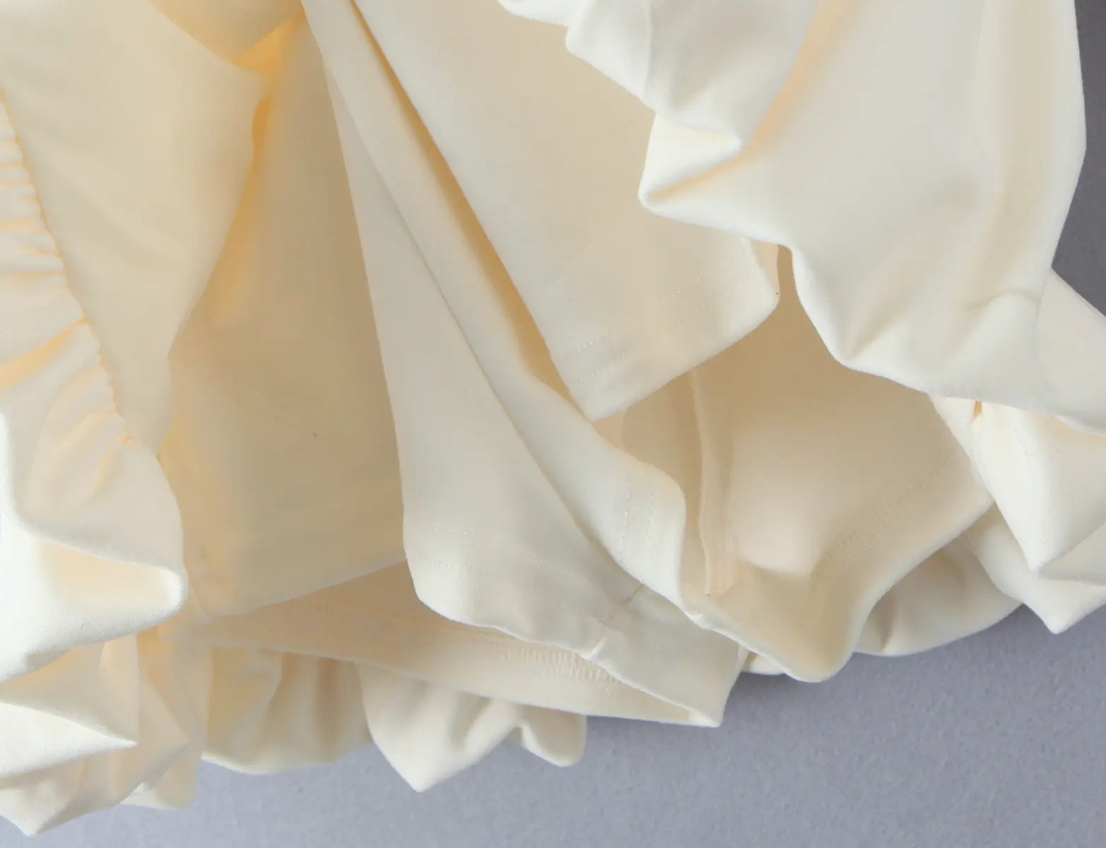Close-up of fabric texture and layered lining on cream-white dress