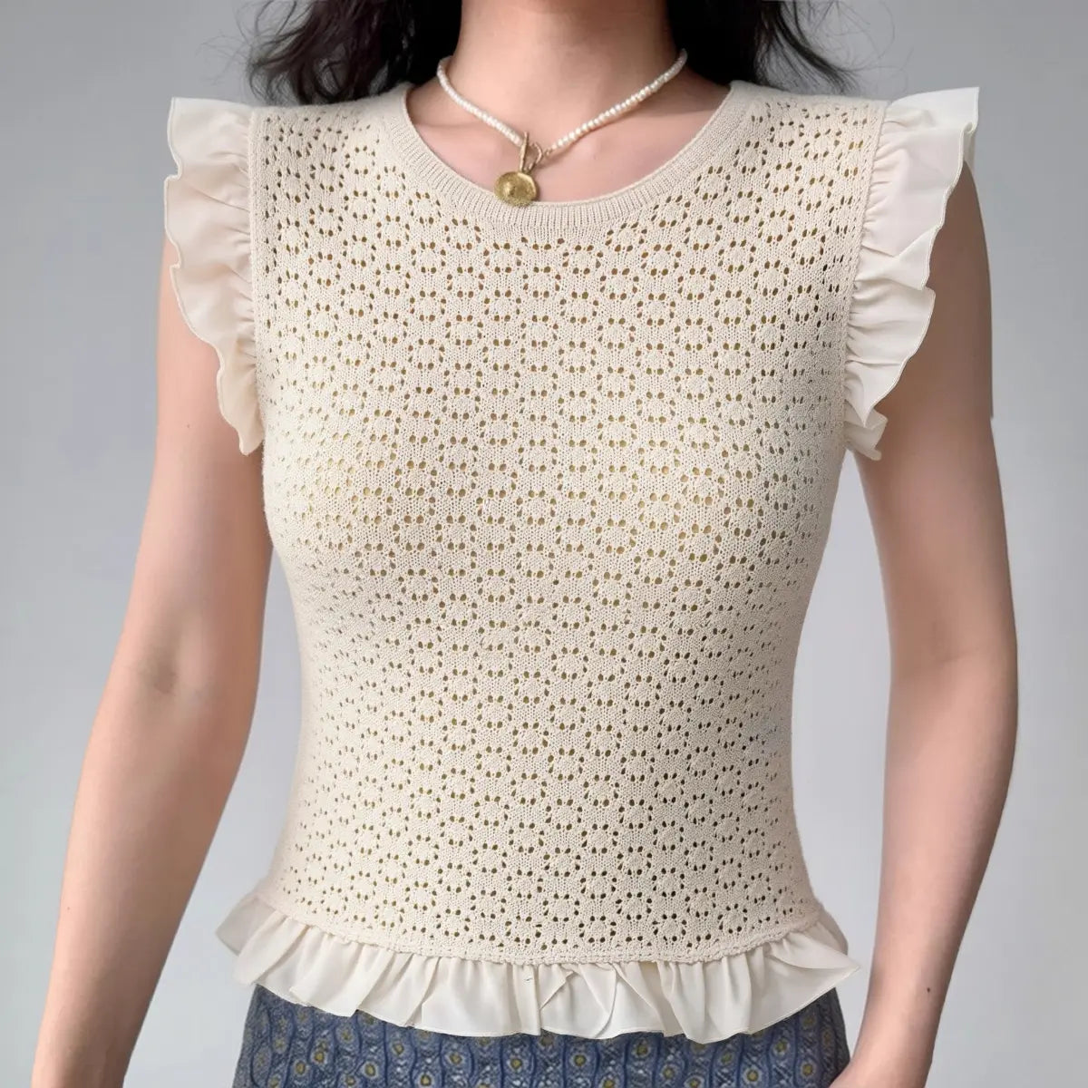 Model wearing cream white lace-knit top with ruffle sleeves and hem, textured feminine blouse