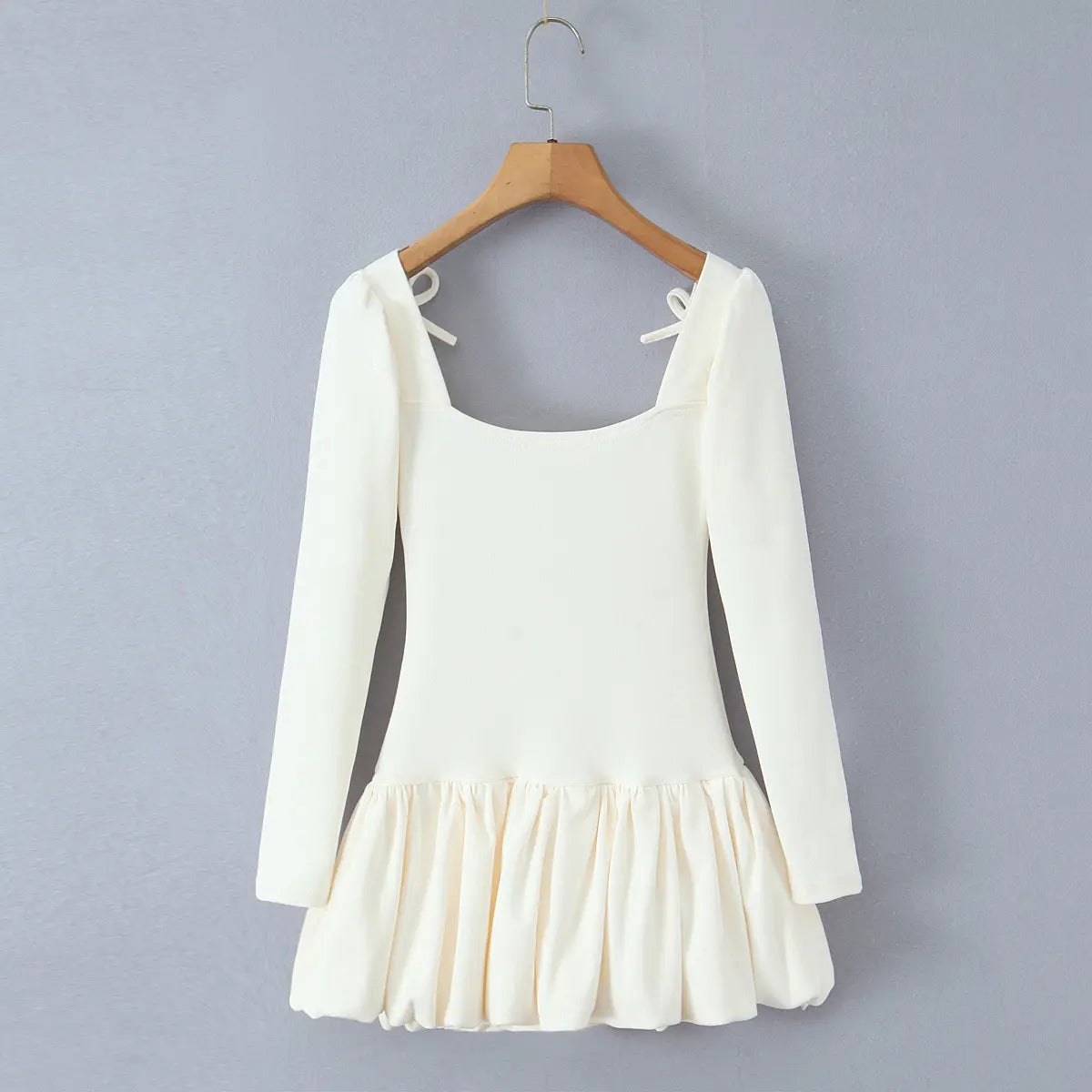 Cream-white long-sleeve dress hanging on wooden hanger, back view