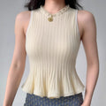 Model wearing cream white ribbed-knit tank with ruffled neckline and peplum hem, fitted sleeveless sweater