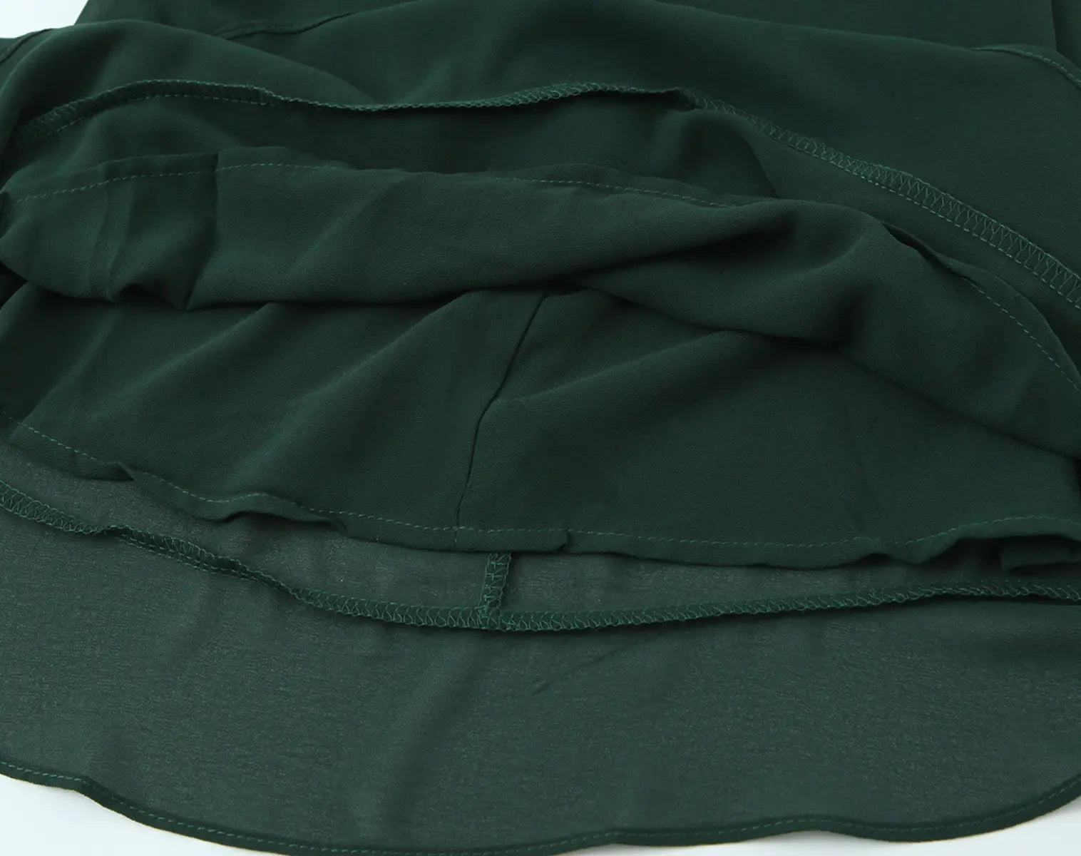 Fabric texture and layered hem detail of dark green cami mini dress