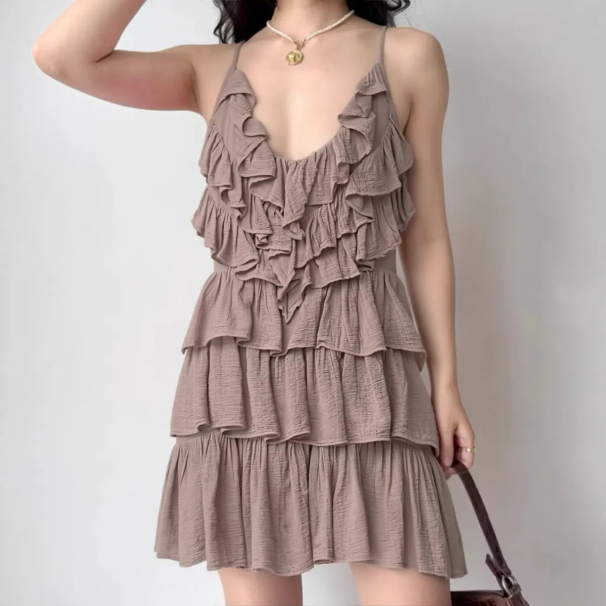 Model wearing dusty pink halter-neck ruffled mini dress with tiered skirt