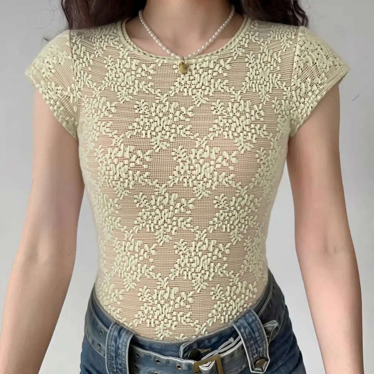 Beige lace top worn by a person on a plain background