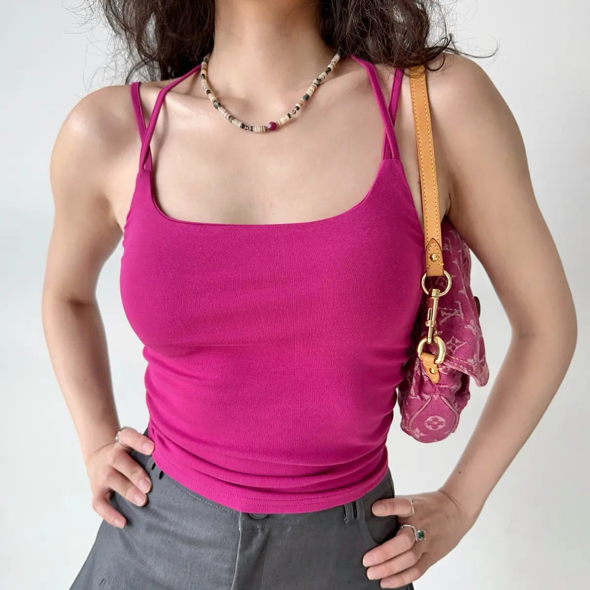 Outfit view of fuchsia cami top styled with gray trousers, highlighting the stretchy ribbed fabric