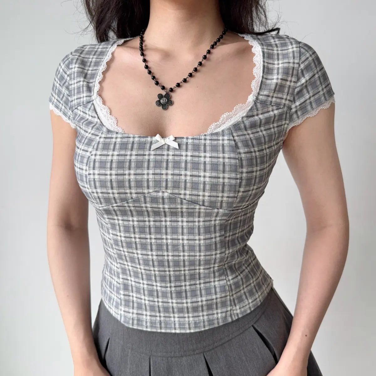 Model wearing gray plaid square-neck top with white lace trim, sweetheart bust and fitted corset-style silhouette