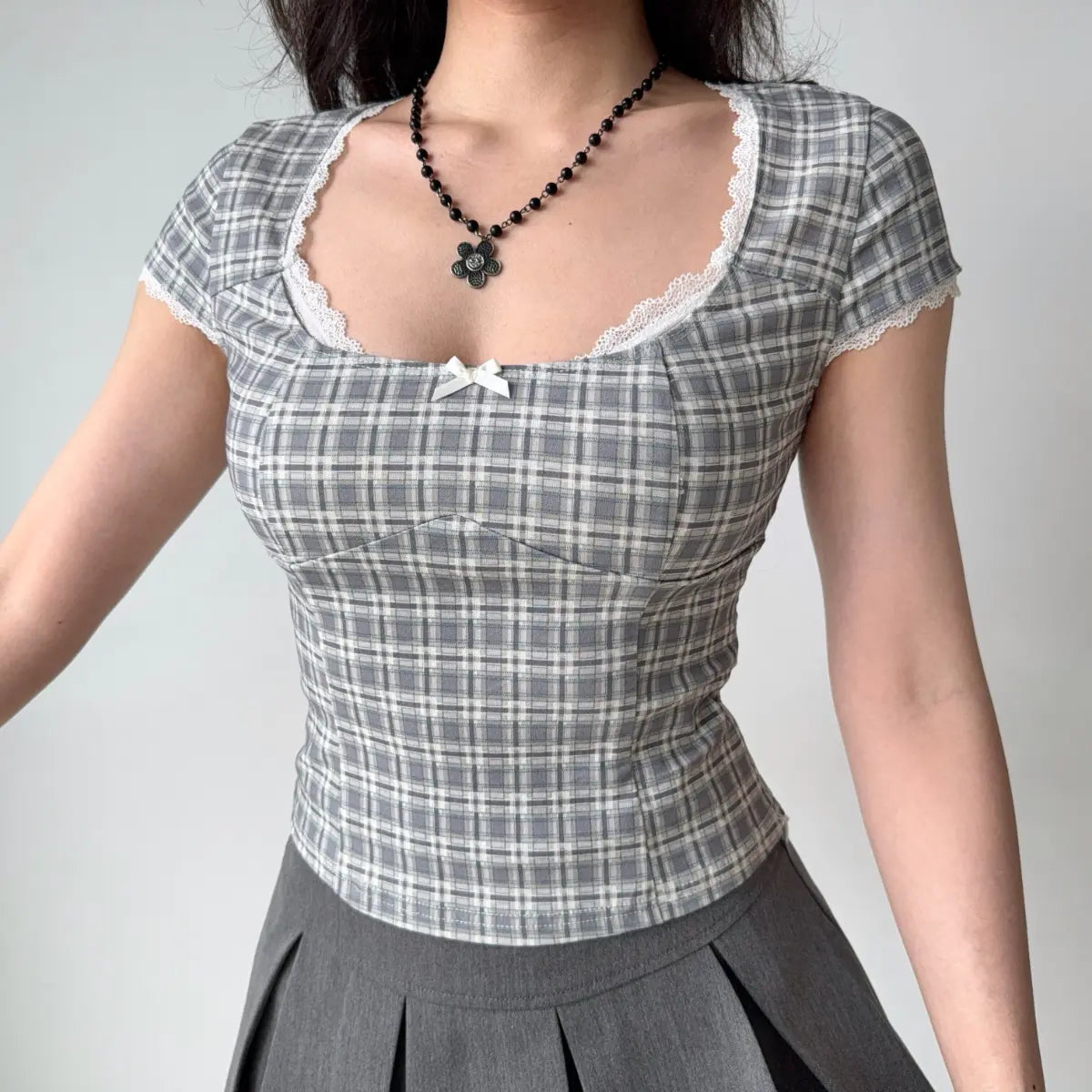 Front view of gray plaid top with delicate lace trim along the neckline and cap sleeves
