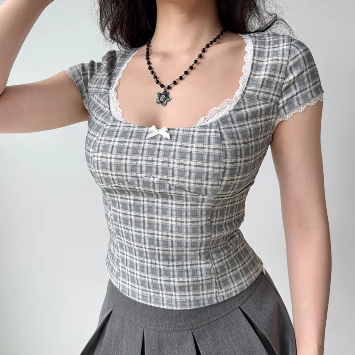 Outfit view of gray plaid lace-trim top styled with a gray pleated skirt