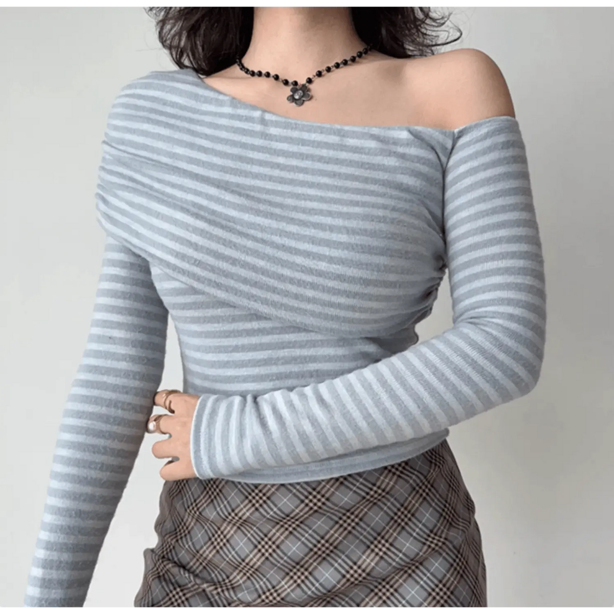 Model wearing grey‑white stripe draped off‑shoulder long sleeve fitted top, casual pose
