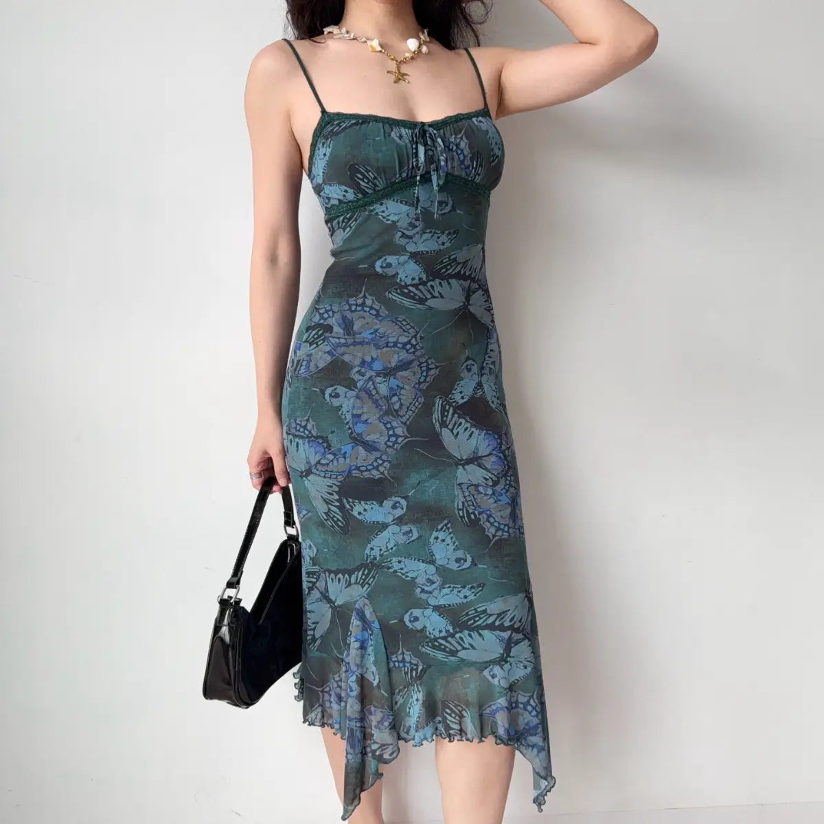 Model wearing green butterfly print spaghetti strap dress, front pose