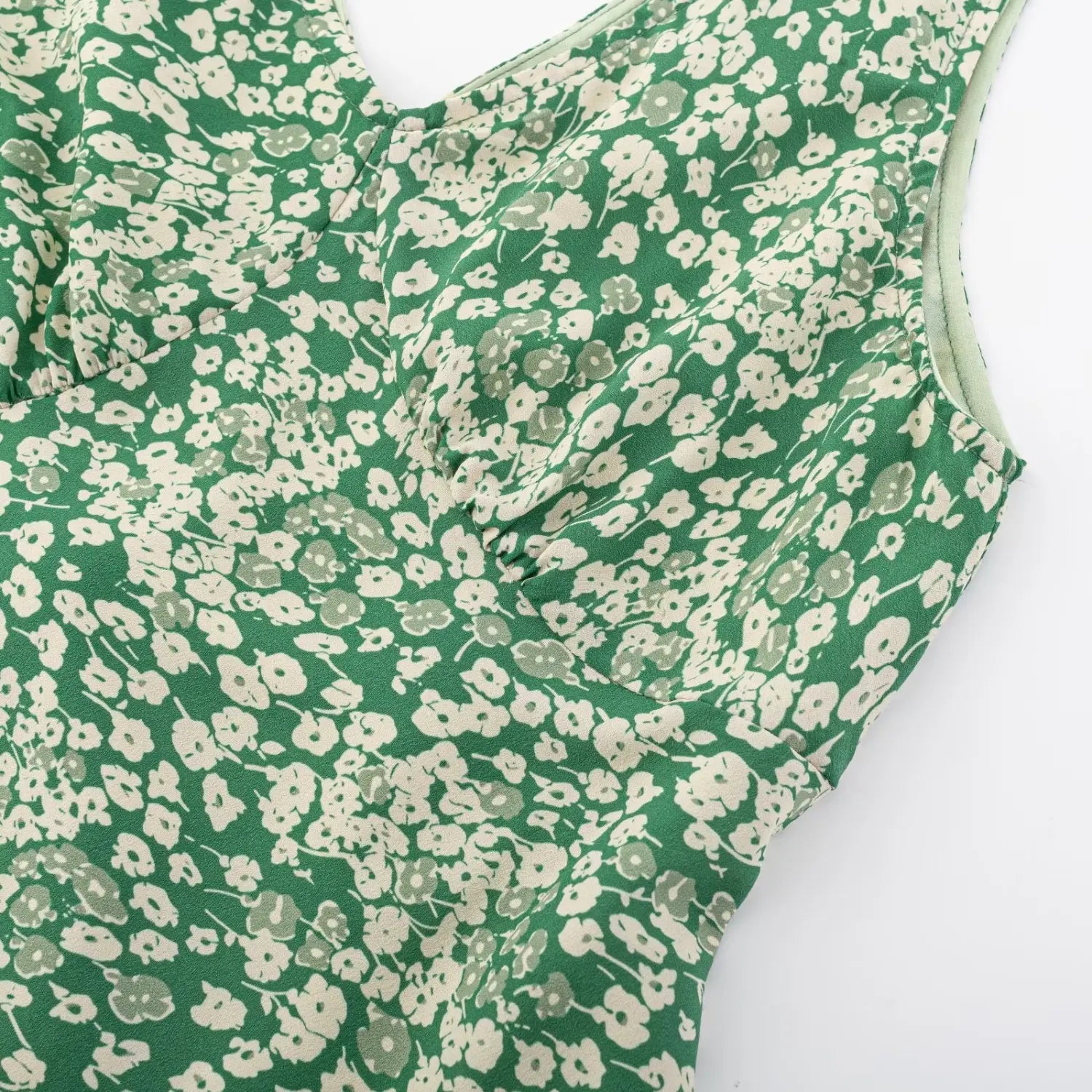 Macro shot of chest ruched craft on green floral midi dress, clear small white flower print texture