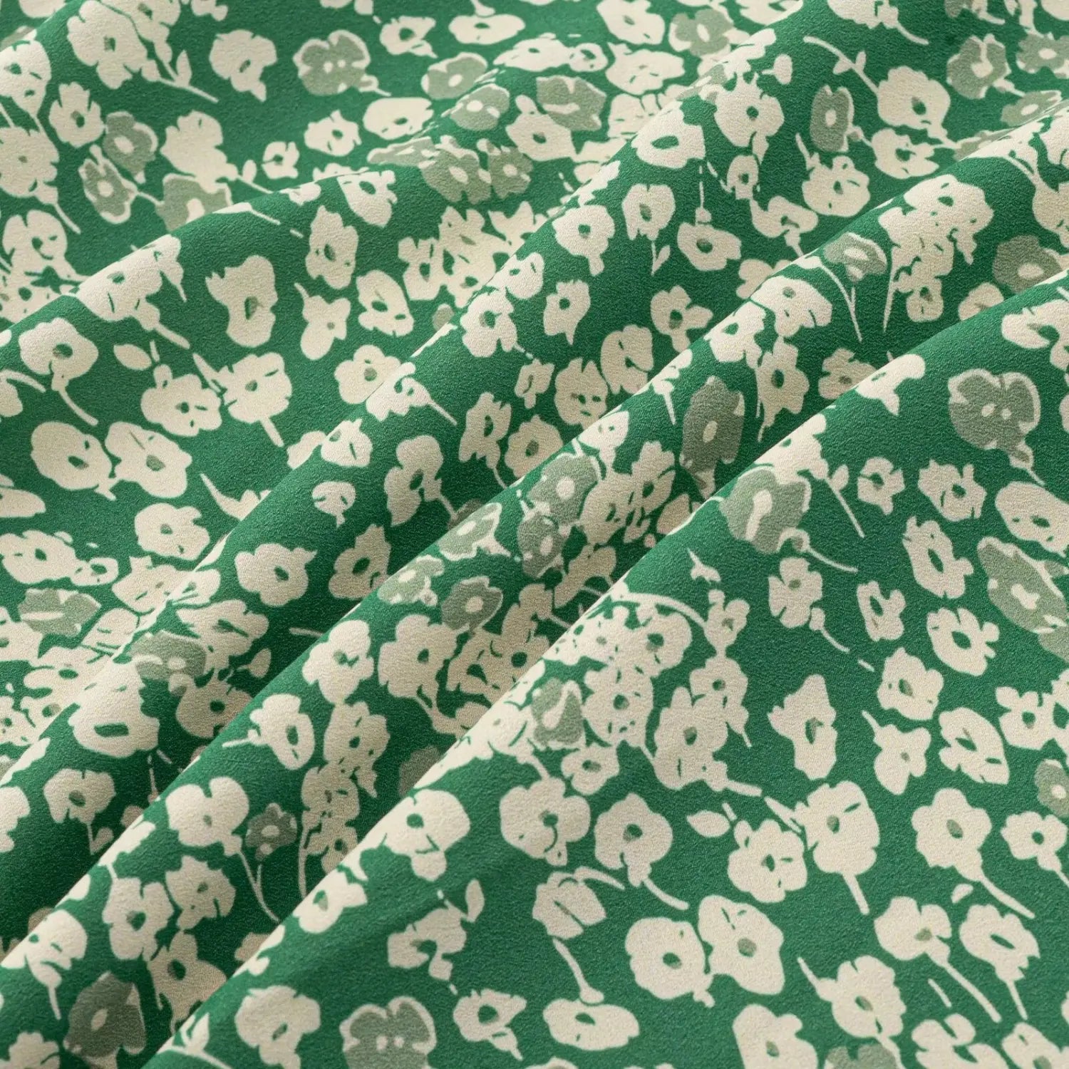Fabric texture close-up of green floral maxi dress, soft lightweight chiffon with scattered white flower print