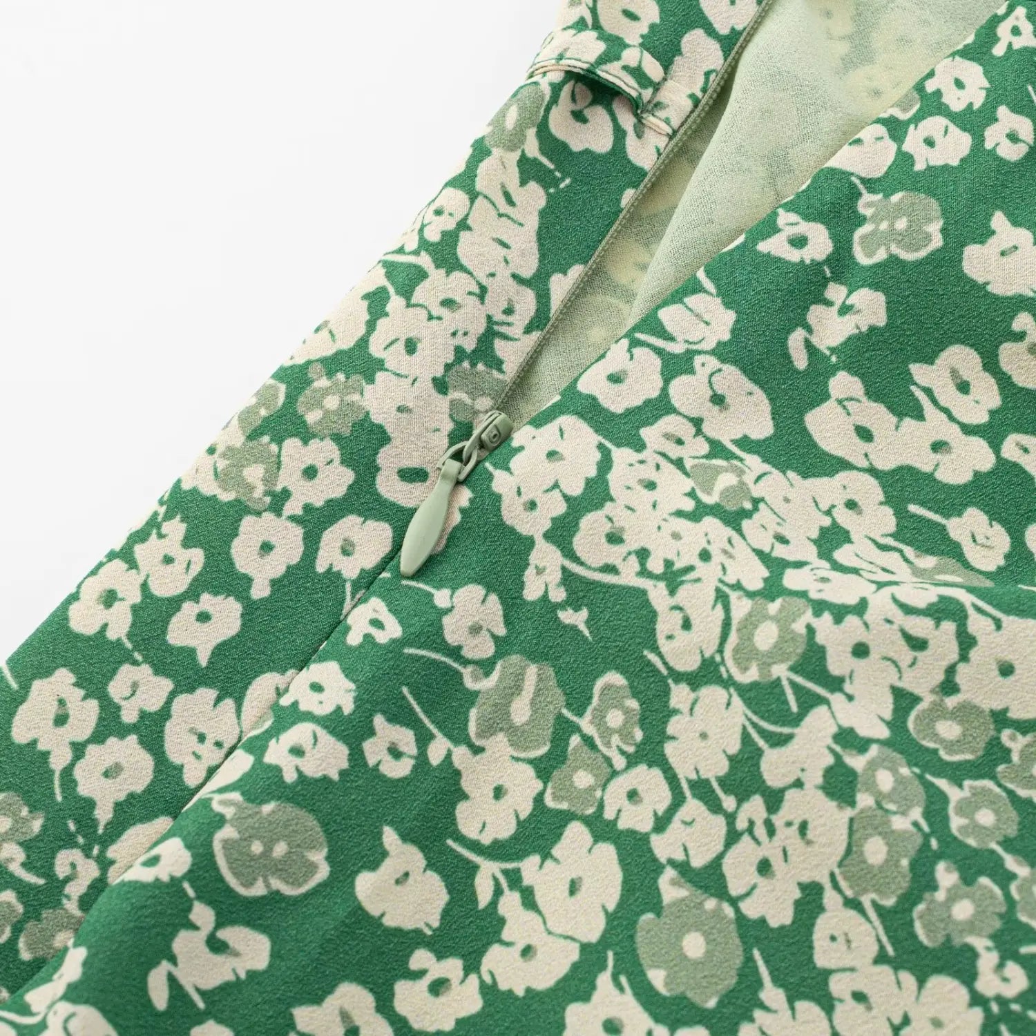 Hidden side zipper detail of green floral sleeveless dress, matching light green zipper and inner lining